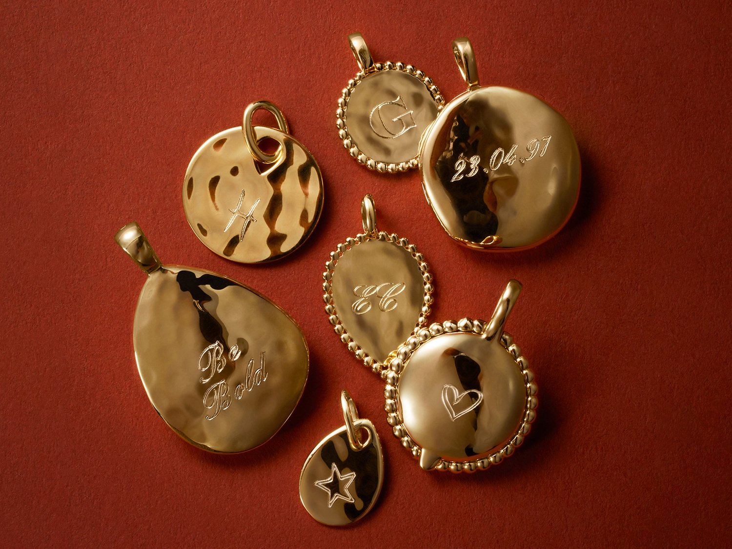 A collection of gold pendants, engraved on a red fabric background